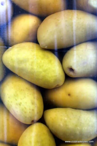 Close-up of green Lucques olives through the glass jar